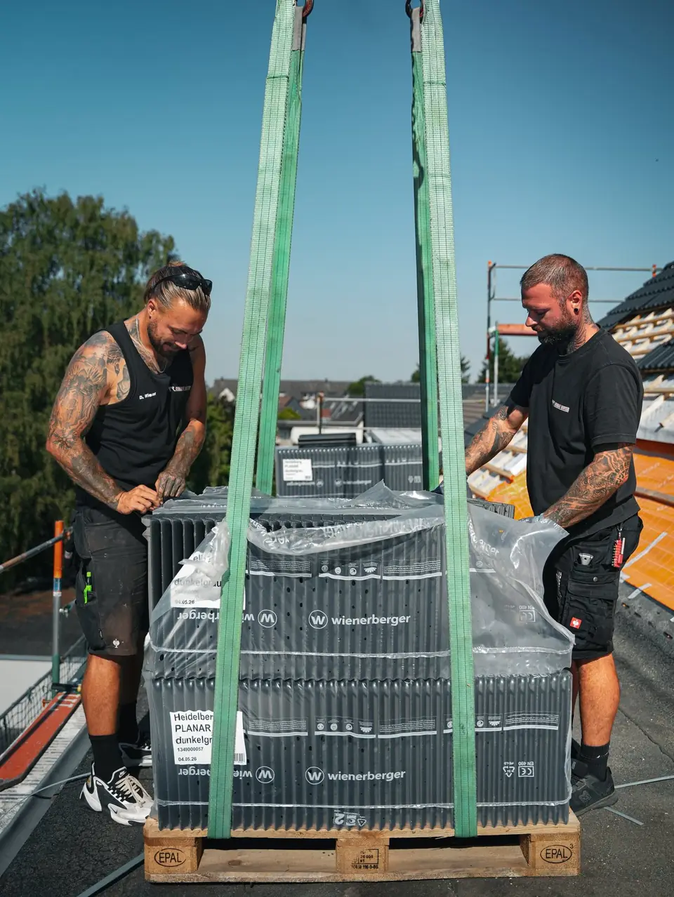 Dachziegel werden mit dem Kran auf das Dach gehoben